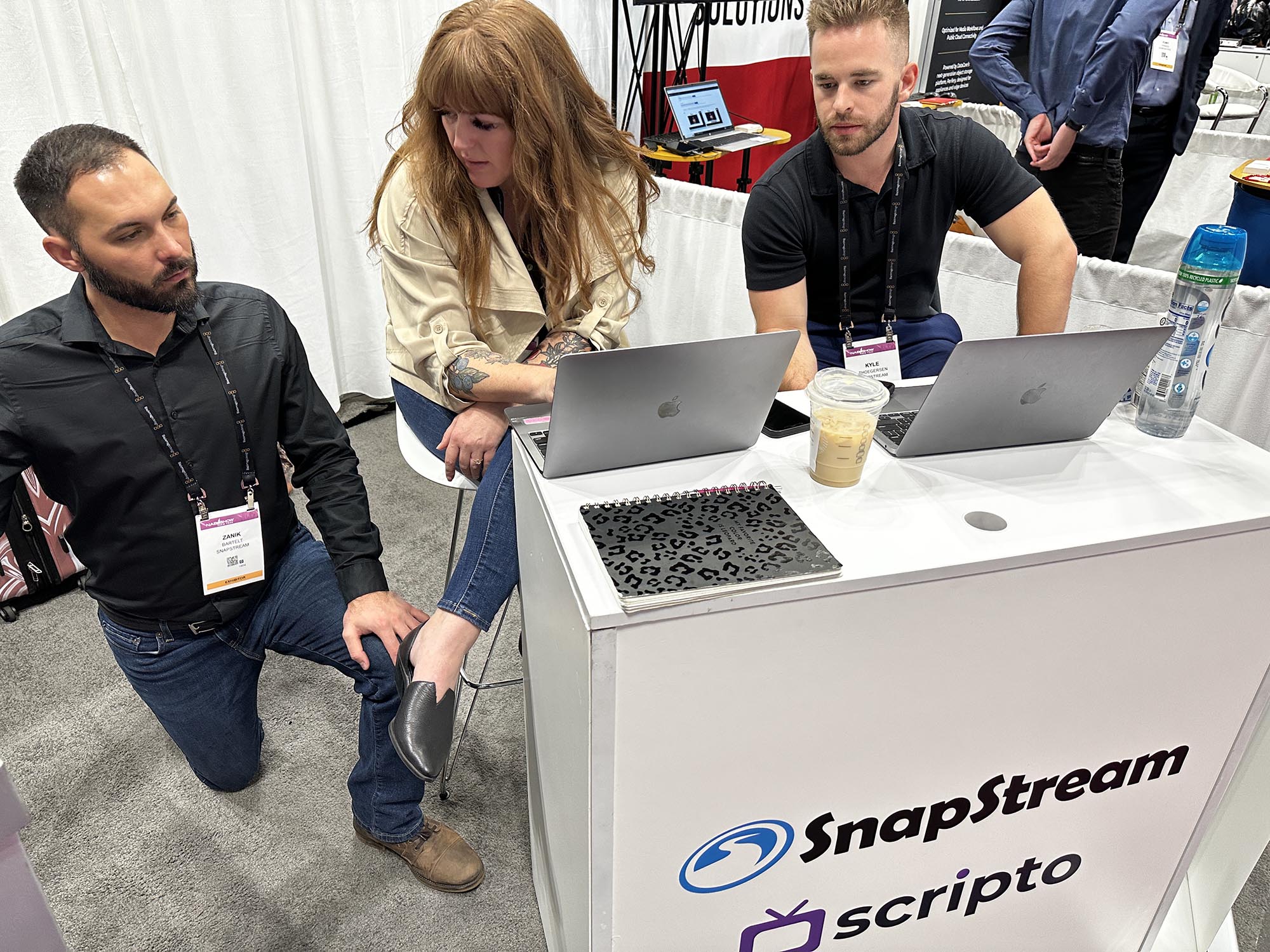 Two men and a woman at a podium with computers